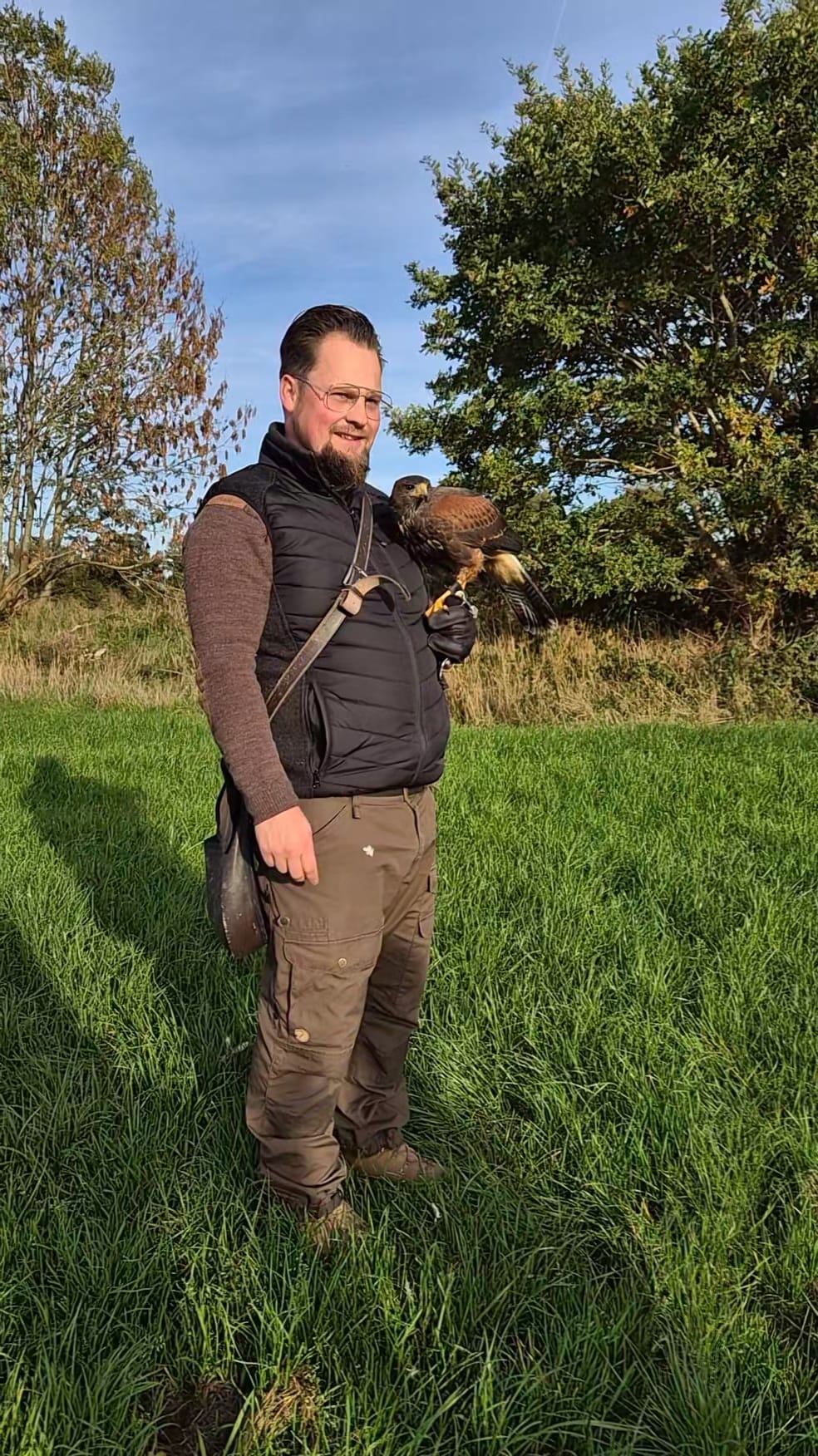 Valkenier met roofvogel in het veld